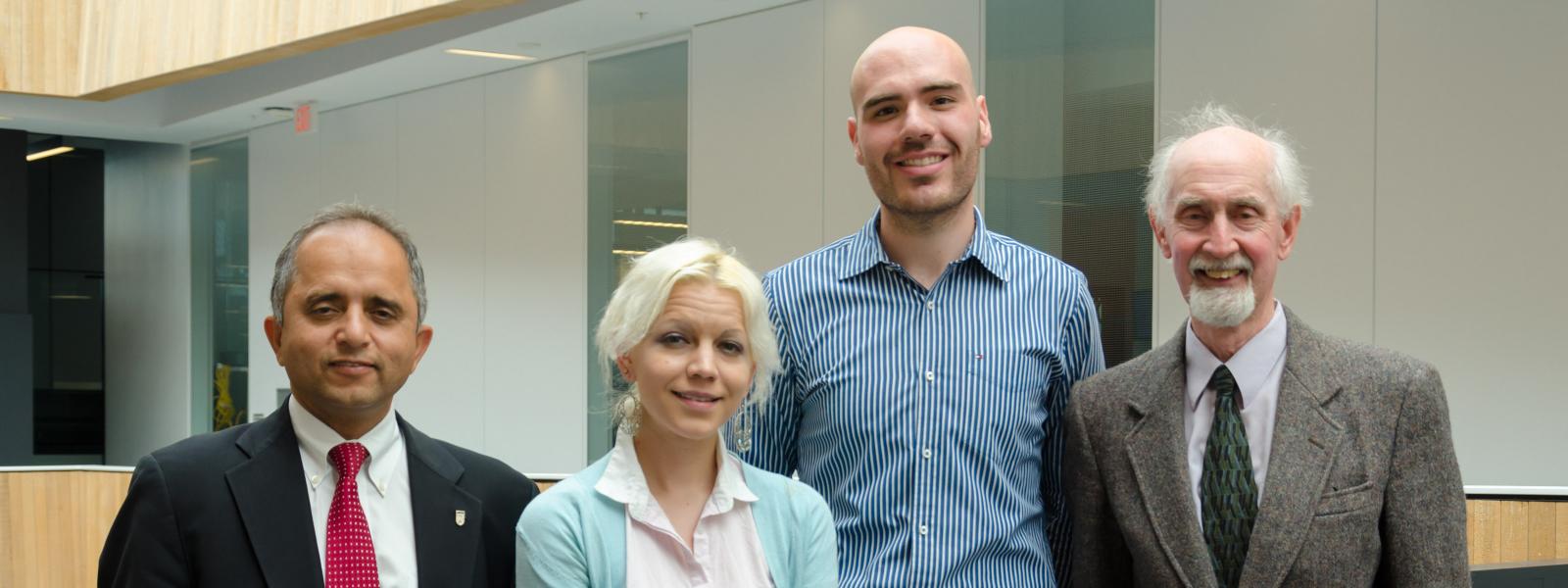 Four people wearing business attire, standing and smiling at the camera.