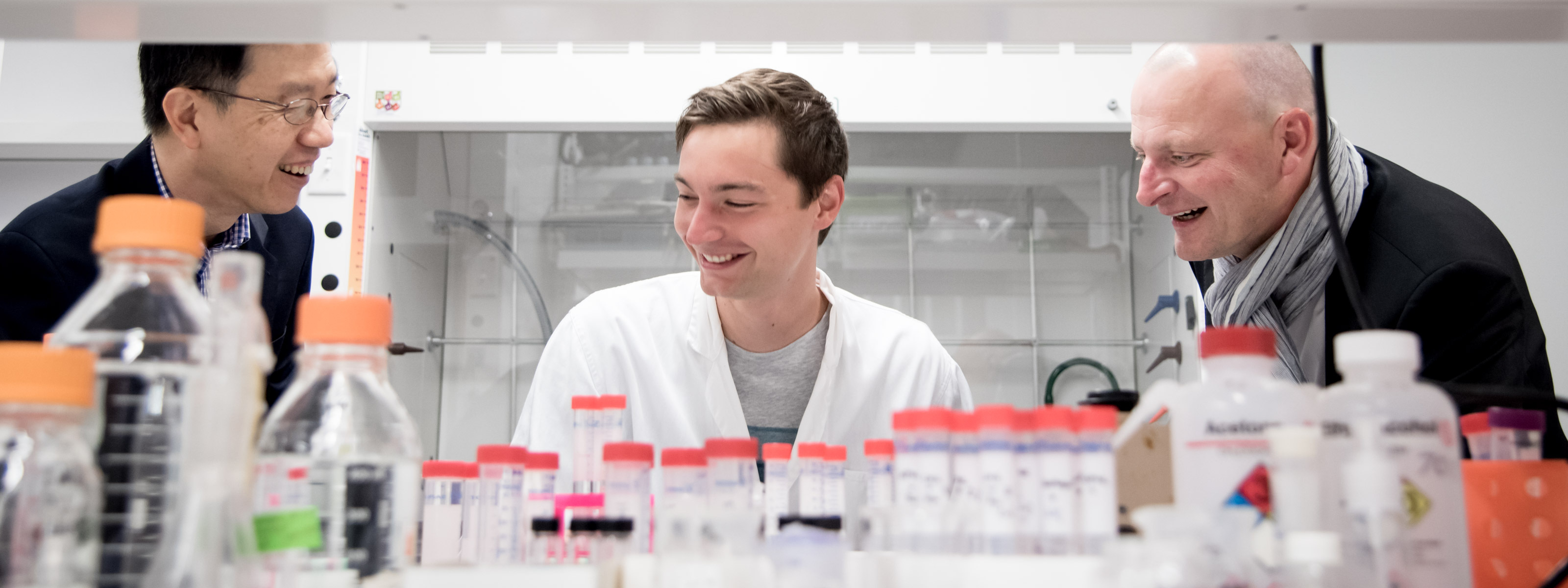 Three people in a lab; there is lab equipment in the foreground.
