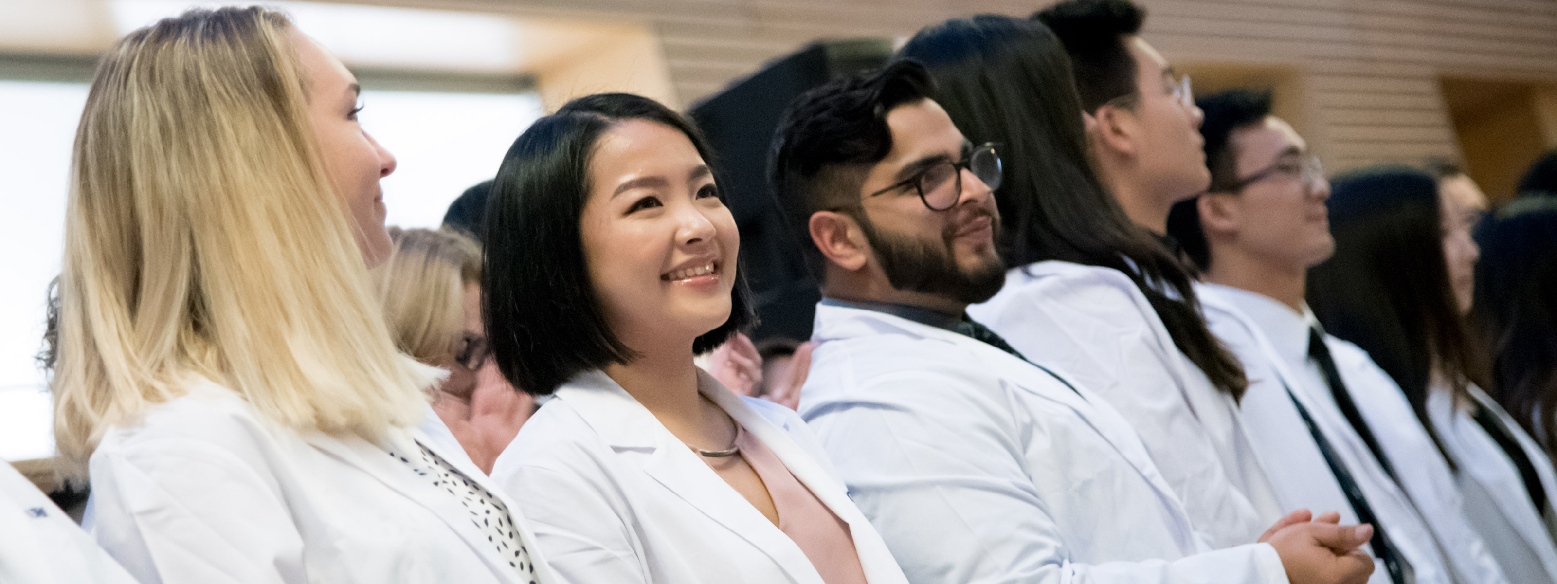 A row of smiling students wearing lab coats.