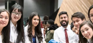 A group of students in lab coats smiling at the camera.