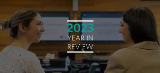 Two students smiling and facing each other, with the text "2023 Year in Review" overlaid between them.