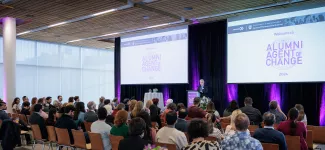 An audience at the Alumni Agent of Change event, listening to a speaker at a podium.