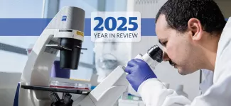 A researcher looking into a microscrope, overlaid with the text "2025 Year in Review".