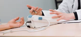 A healthcare practitioner motioning with their hands while conversing with a patient.
