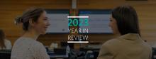 Two students smiling and facing each other, with the text "2023 Year in Review" overlaid between them.