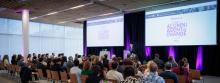 An audience at the Alumni Agent of Change event, listening to a speaker at a podium.