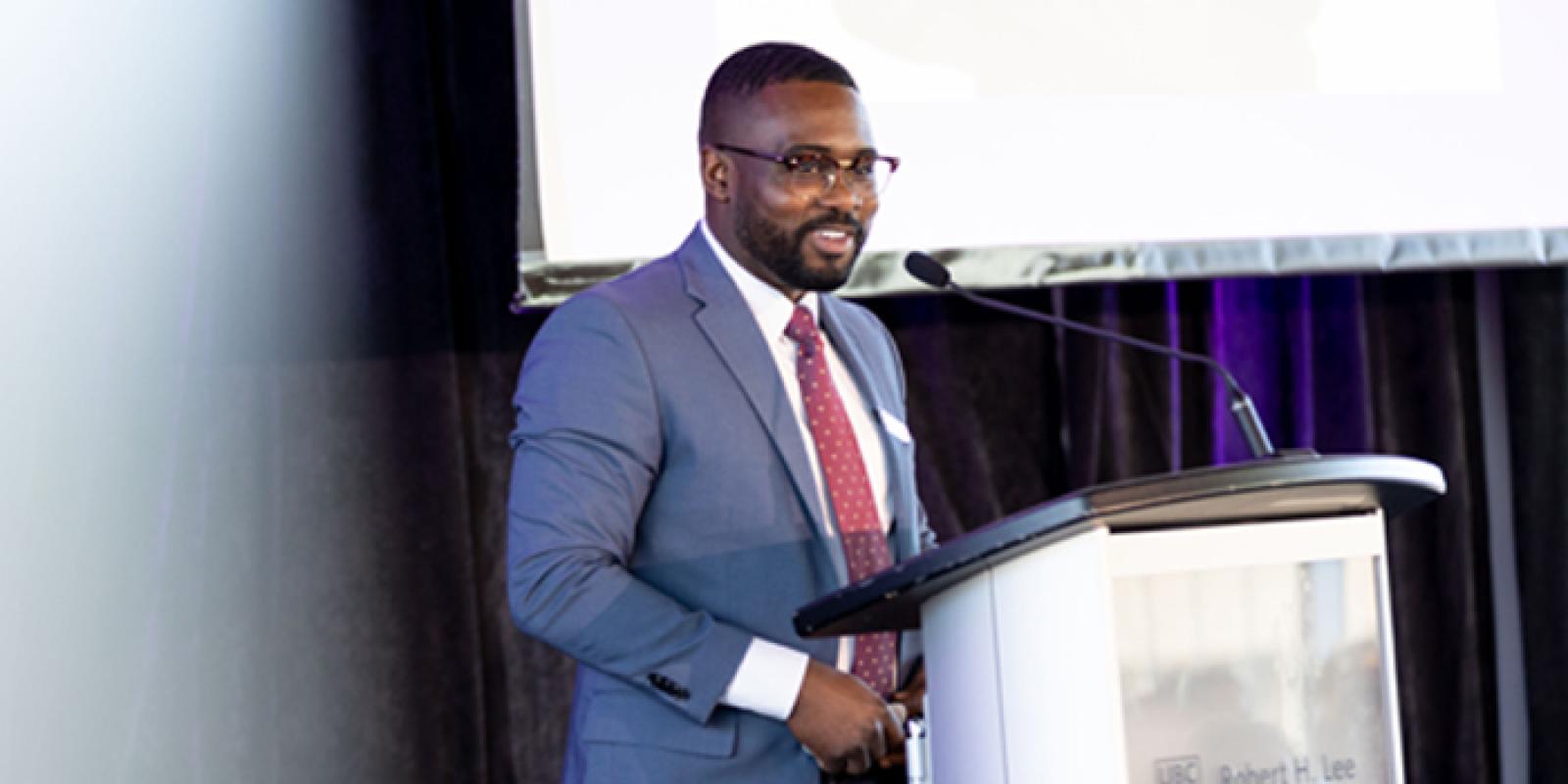 A health care professional on stage, presenting behind a podium.