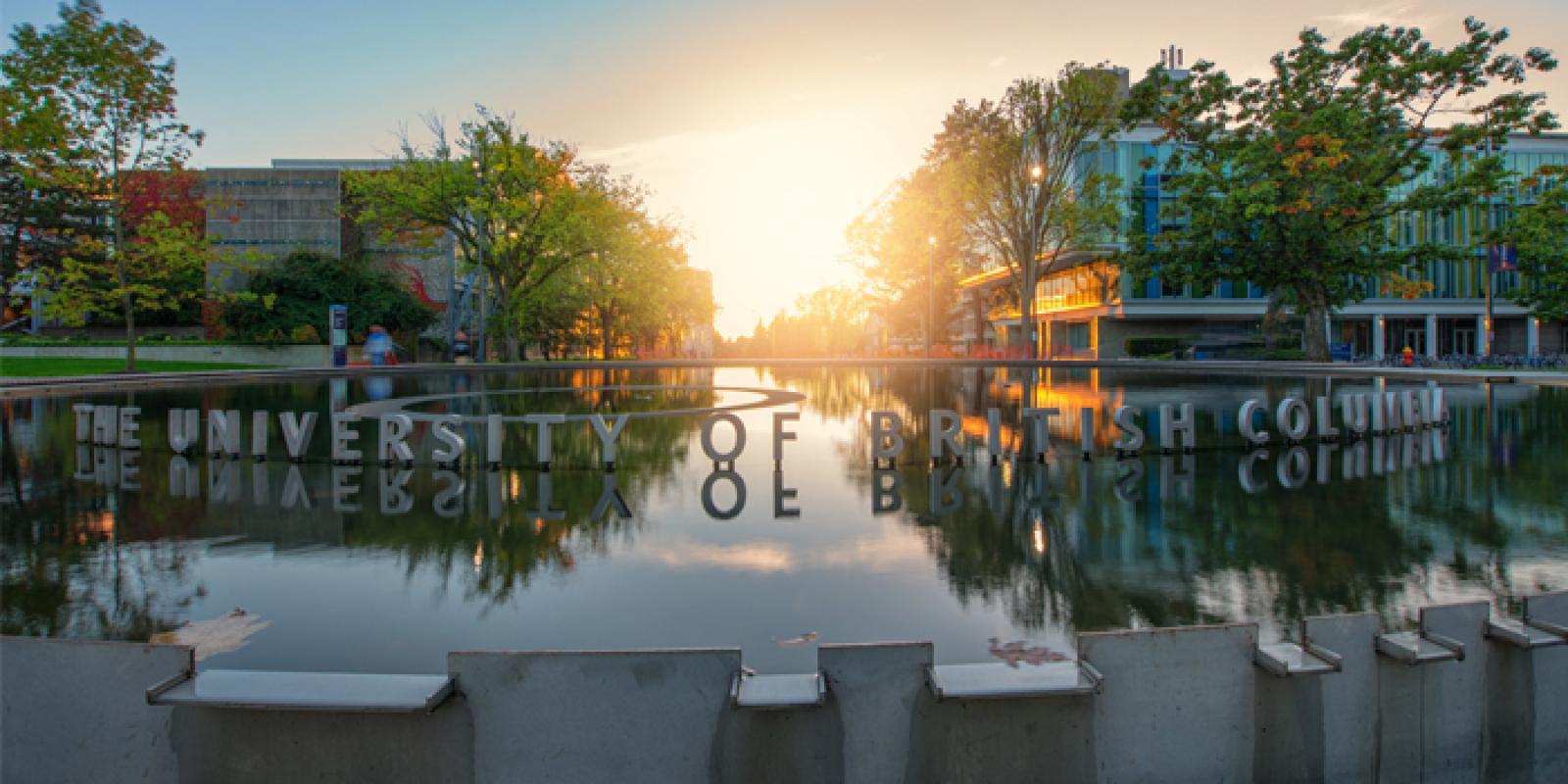 A reflection of the UBC sign in the Martha Piper Plaza pond at sunset.